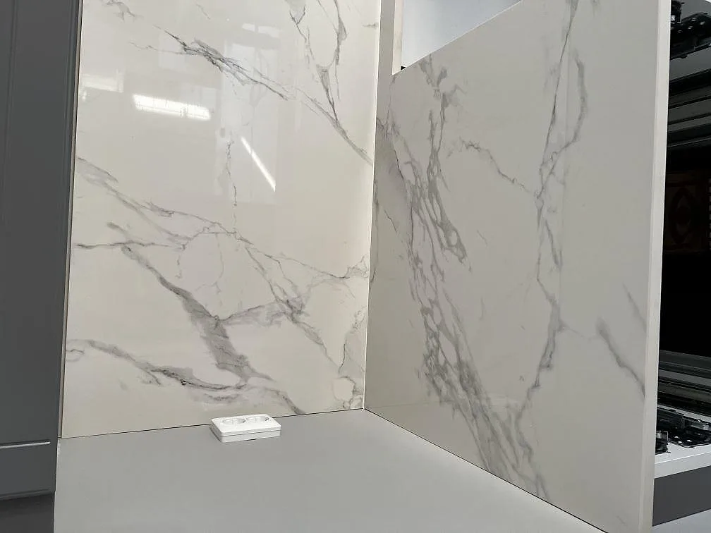 Närbild på polerad Dekton Natura bänkskiva och väggpanel med calacattalik ådring i ett kök i Landskrona.