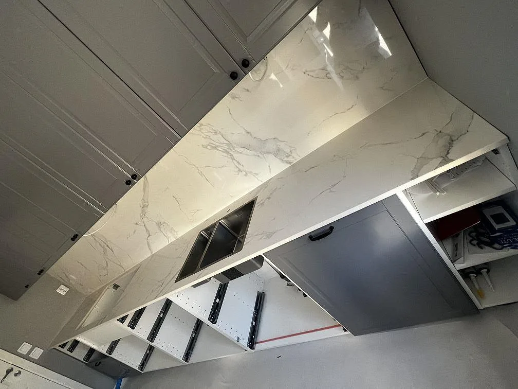 Köksbänk i vit Dekton Natura, polerad keramik med grå ådring, rostfri diskho och högt stänkskydd i Landskrona.