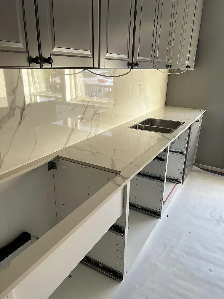 L-formad köksbänkskiva i polerad Dekton Natura keramik med matchande stänkskydd och rostfri diskho i Landskrona.