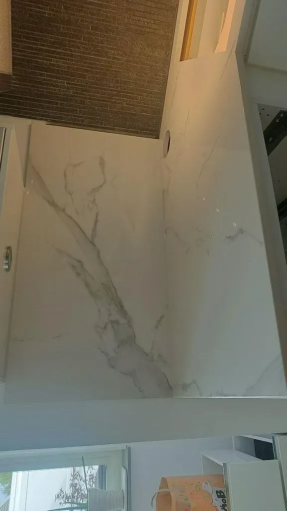 Köksbänkskiva i polerad Dekton Natura med urtag för blandare vid fönstret i ett ljust kök i Växjö.