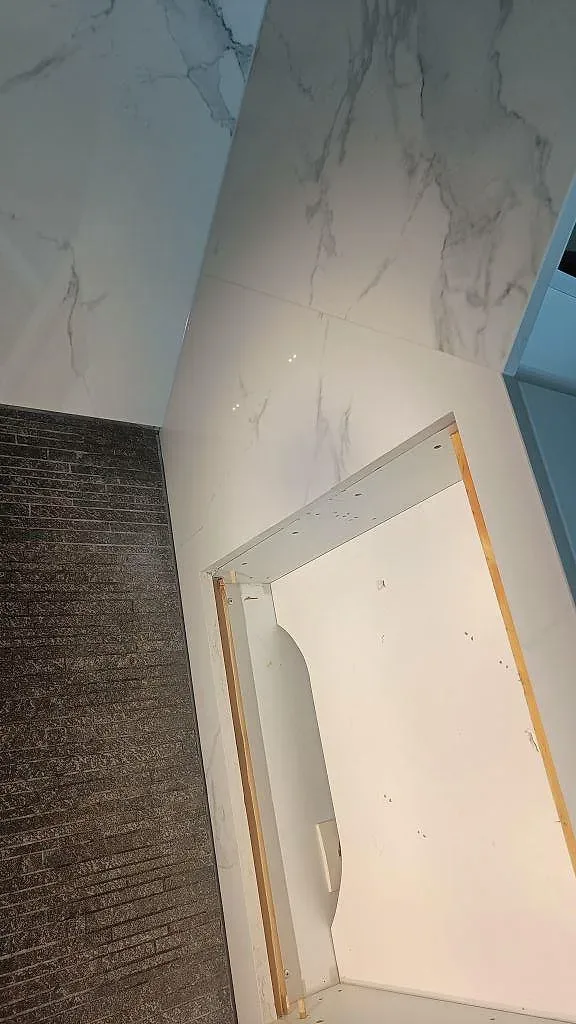 Hörnparti av köksbänkskiva i polerad Dekton Natura med marmorlik ådring och förberedda urtag i ett kök i Växjö.
