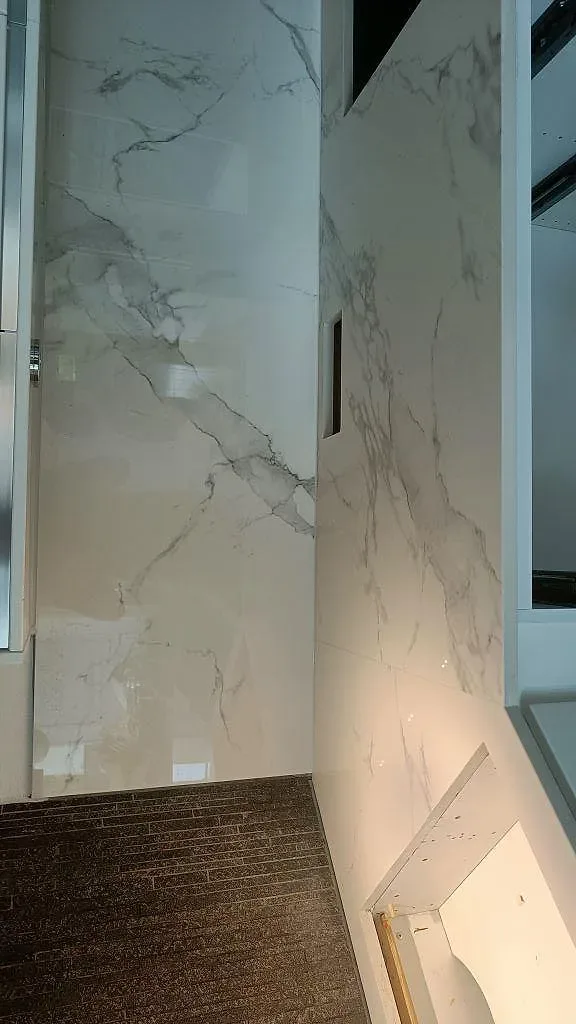 Polerad Dekton Natura köksbänkskiva med diskret grå ådring och uppvikt stänkskydd i samma sten i ett kök i Växjö.