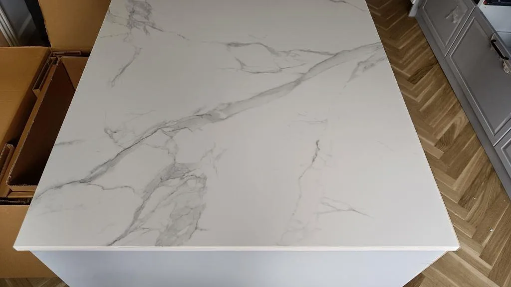 Topvy av köksö i polerad Dekton Natura med fina grå ådror mot vit botten i ett kök i Vanløse.