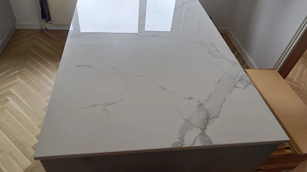 Topvy av polerad Dekton Natura med kraftig grågrön marmorådring på en köksö i ett kök i Vanløse.