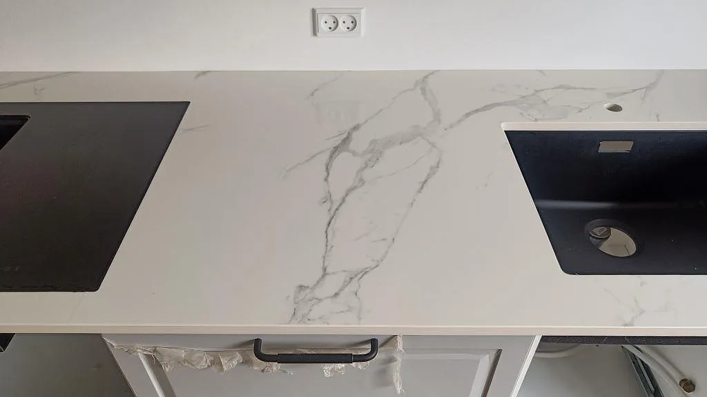 Köksbänkskiva i Dekton Natura med två underlimmade svarta kompositdiskhoar och plats för induktionshäll i ett kök i Vanløse.