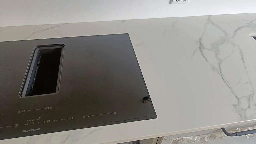 Induktionshäll med integrerad fläkt infälld i en köksbänkskiva av Dekton Natura keramik i ett kök i Vanløse.
