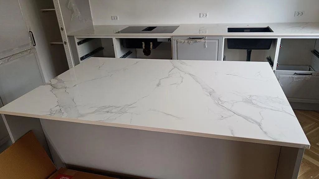Köksbänkskiva och köksö i Dekton Natura, polerad keramik med grå marmorådring, monterad i ett kök under montering i Vanløse.