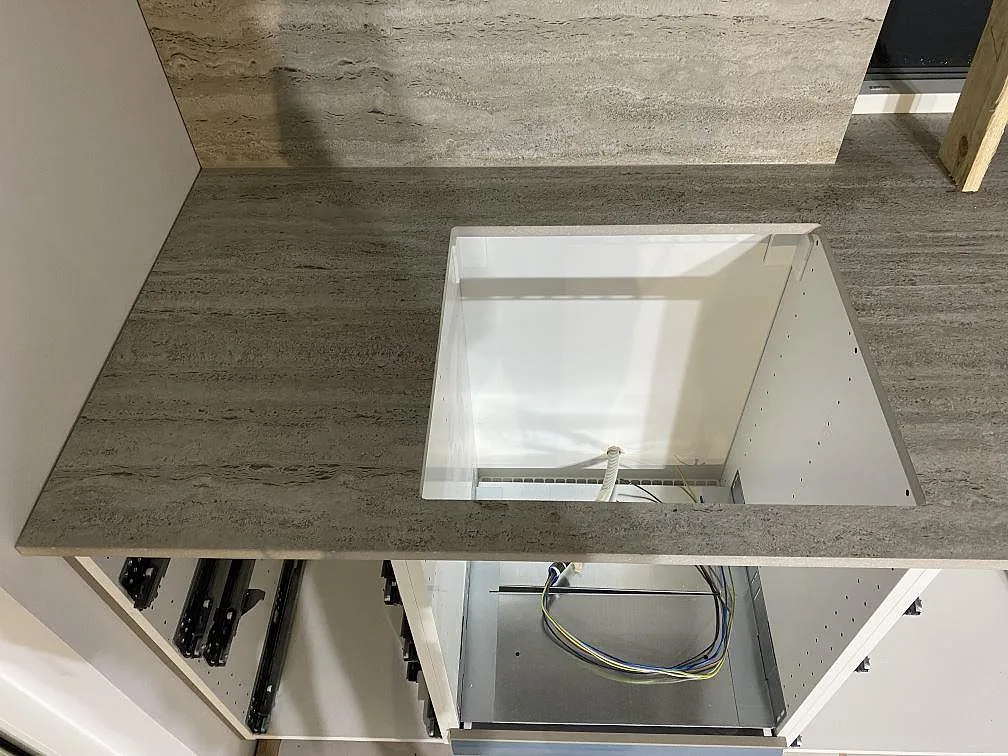 Köksbänkskiva i matt Dekton Nebu keramik med öppning vid diskzonen och stänkskydd i samma material under montering i Borrby.