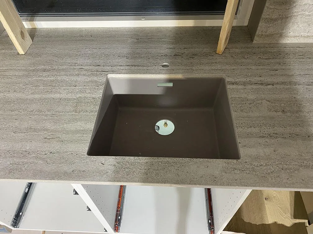 Mörk diskho i en köksbänkskiva av matt Dekton Nebu keramik, med fönster och stänkskydd bakom i Borrby.