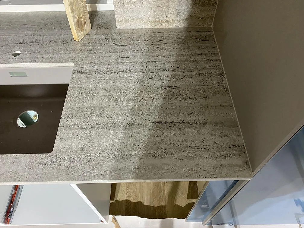 Detalj av matt Dekton Nebu keramik på köksbänkskiva i Borrby, med gråbeige ådring, diskho och sidovägg.