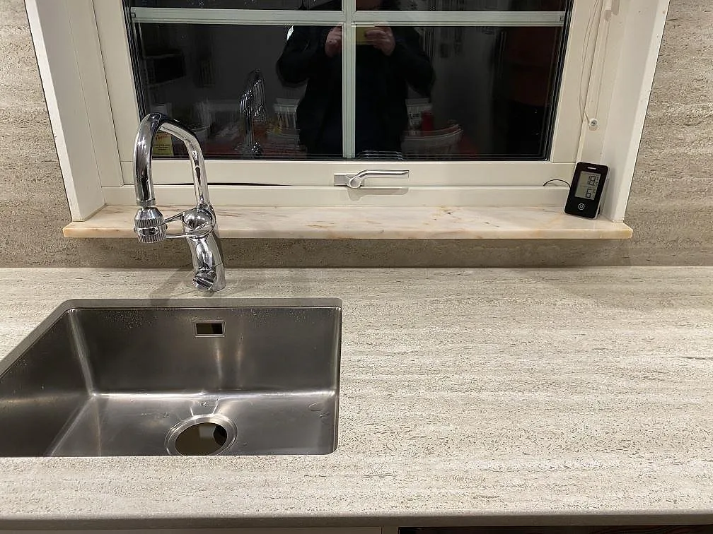 Underlimmad rostfri diskho med köksblandare i matt Dekton Nebu bänkskiva, varmt gråbeige keramik med travertinliknande ådring, Upplands Väsby.