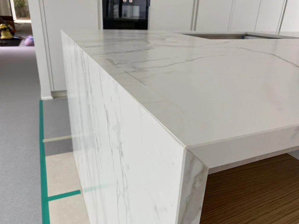 Sidodetalj av köksö i matt Dekton Neural, med sammanhängande bänkskiva och gavel i Ålsgårde.
