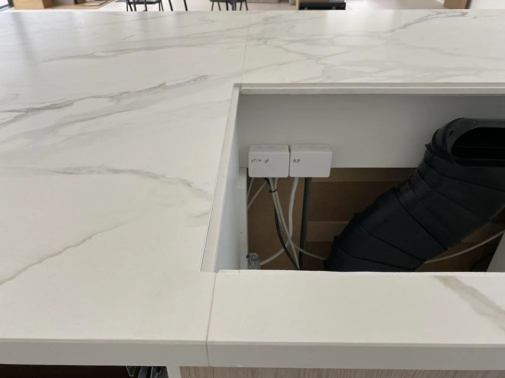 Detalj av öppning i matt Dekton Neural, ljus keramikbänkskiva med grå ådring under montering i Ålsgårde.