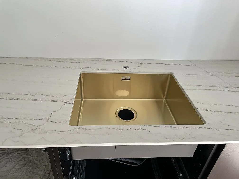 Närbild på matt Dekton Neural som köksbänkskiva med underlimmad guldtonad diskho i ett kök i Frederiksberg.