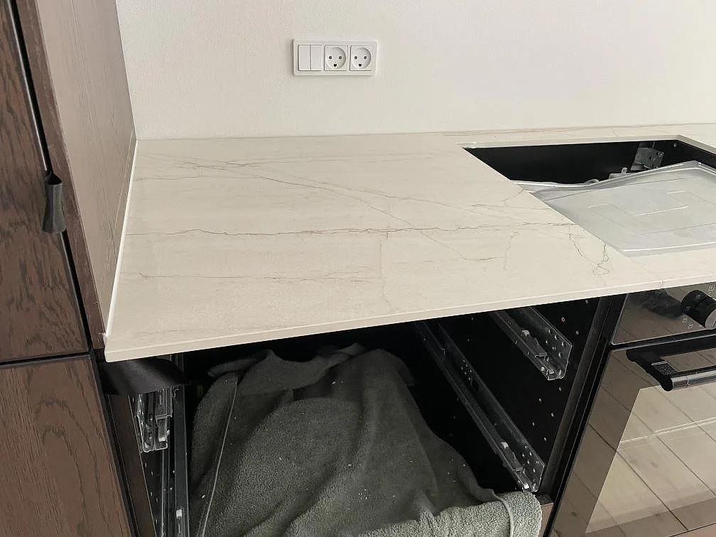 Detalj av matt Dekton Neural vid hällöppning, ljus keramisk bänkskiva med grå ådring i köket i Frederiksberg.
