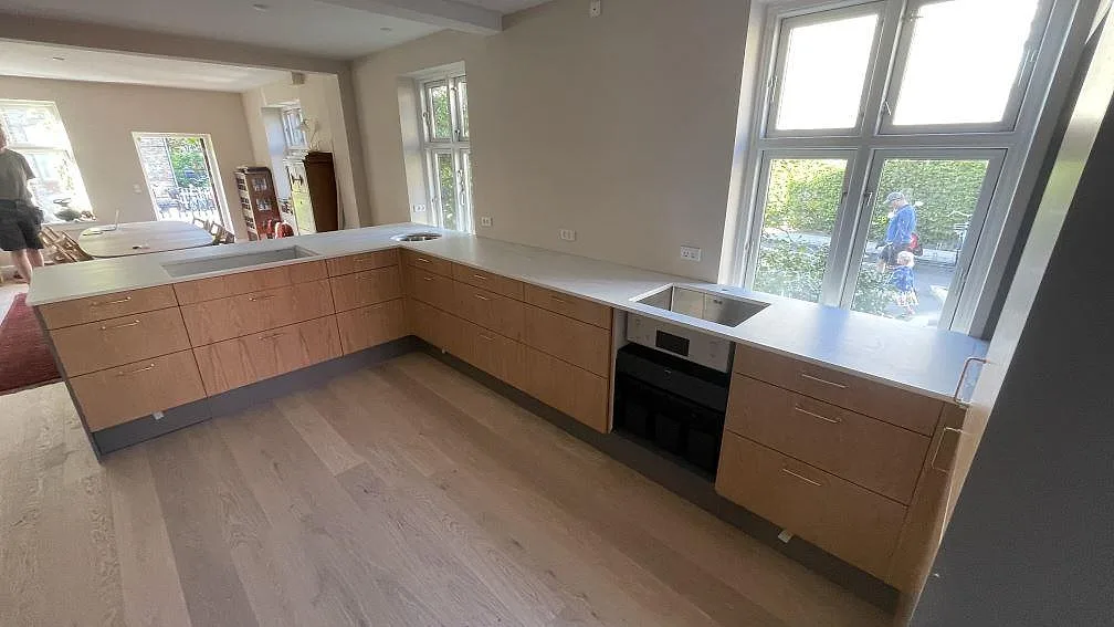 Köksbänkskiva i Dekton Neural med infälld induktionshäll och rund diskho i ett kök med oljad ekinredning i København V.