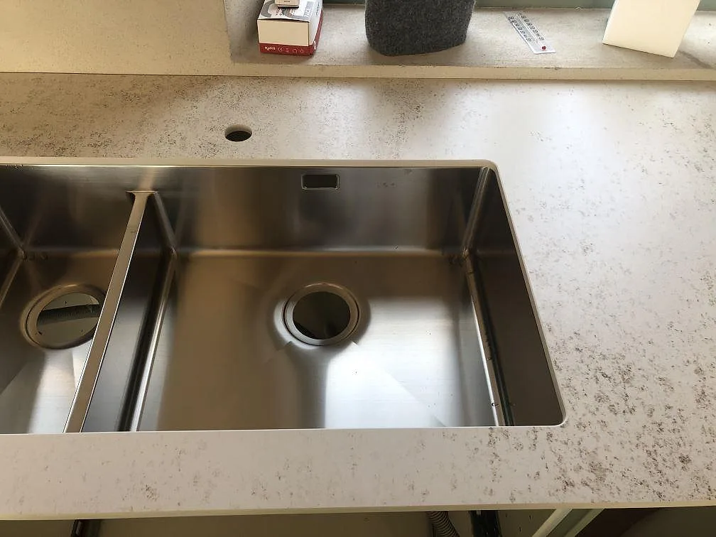 Dubbel underlimmad rostfri diskho i en köksbänkskiva av Dekton Nilium, matt yta med diskret ådring, i Båstad.