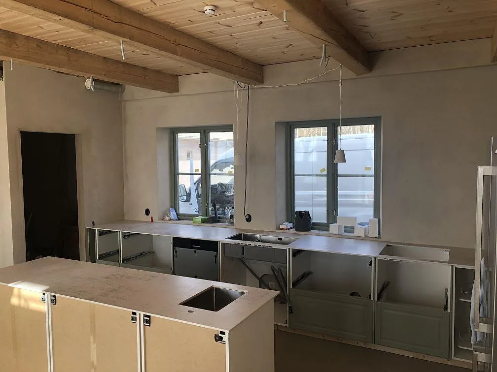 Mid-install kök i Dekton Nilium med köksö och perimeterbänk, öppna stommar och stora fönster, i Båstad.