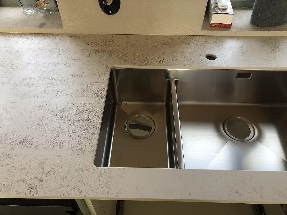 Köksbänkskiva i Dekton Nilium med två underlimmade rostfria diskhoar och hål för kran, sett uppifrån, i ett kök i Båstad.