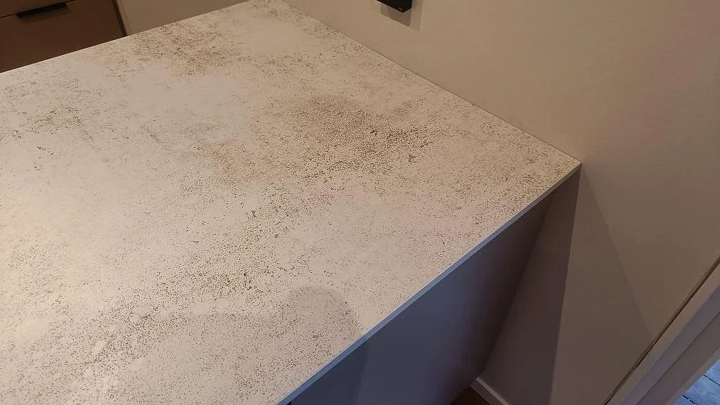 Närbild på köksöns skiva i matt Dekton Nilium med betongliknande mönster och rak kant i Hörby.