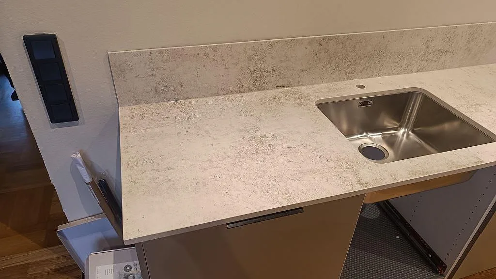 Närbild på matt Dekton Nilium vid diskhon, med stänkskydd och ljusa köksstommar i Hörby.