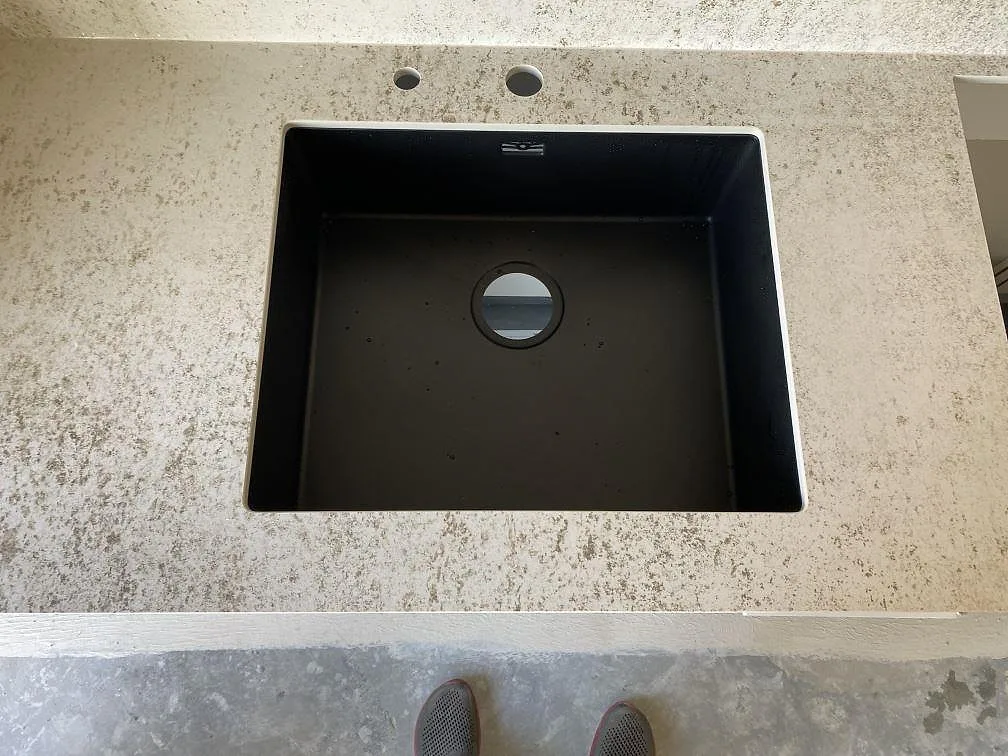 Detalj av svart ho i en matt Dekton Nilium bänkskiva med kranhål och ljus spräcklig keramik i Tygelsjö.
