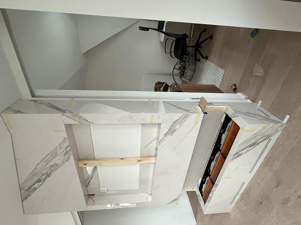 Vit Dekton Olimpo köksbänkskiva med uppvikt stänkkant och eluttag, polerad yta i ett kök i Göteborg.