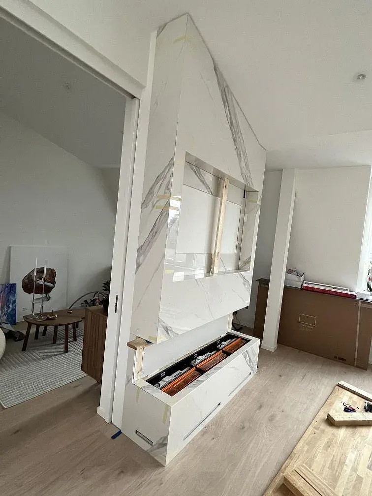 Vit marmorlik Dekton Olimpo köksbänkskiva på köksö med öppna stommar under, polerad yta, i ett kök i Göteborg.