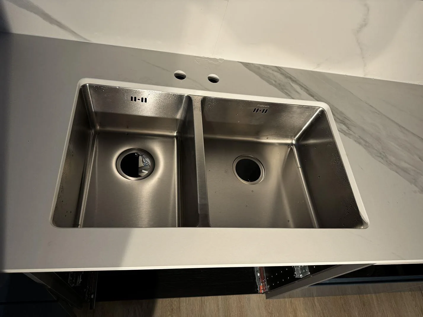 Närbild på matt Dekton Opera Velvet runt en rostfri dubbelho med matchande stänkskydd i Malmö.