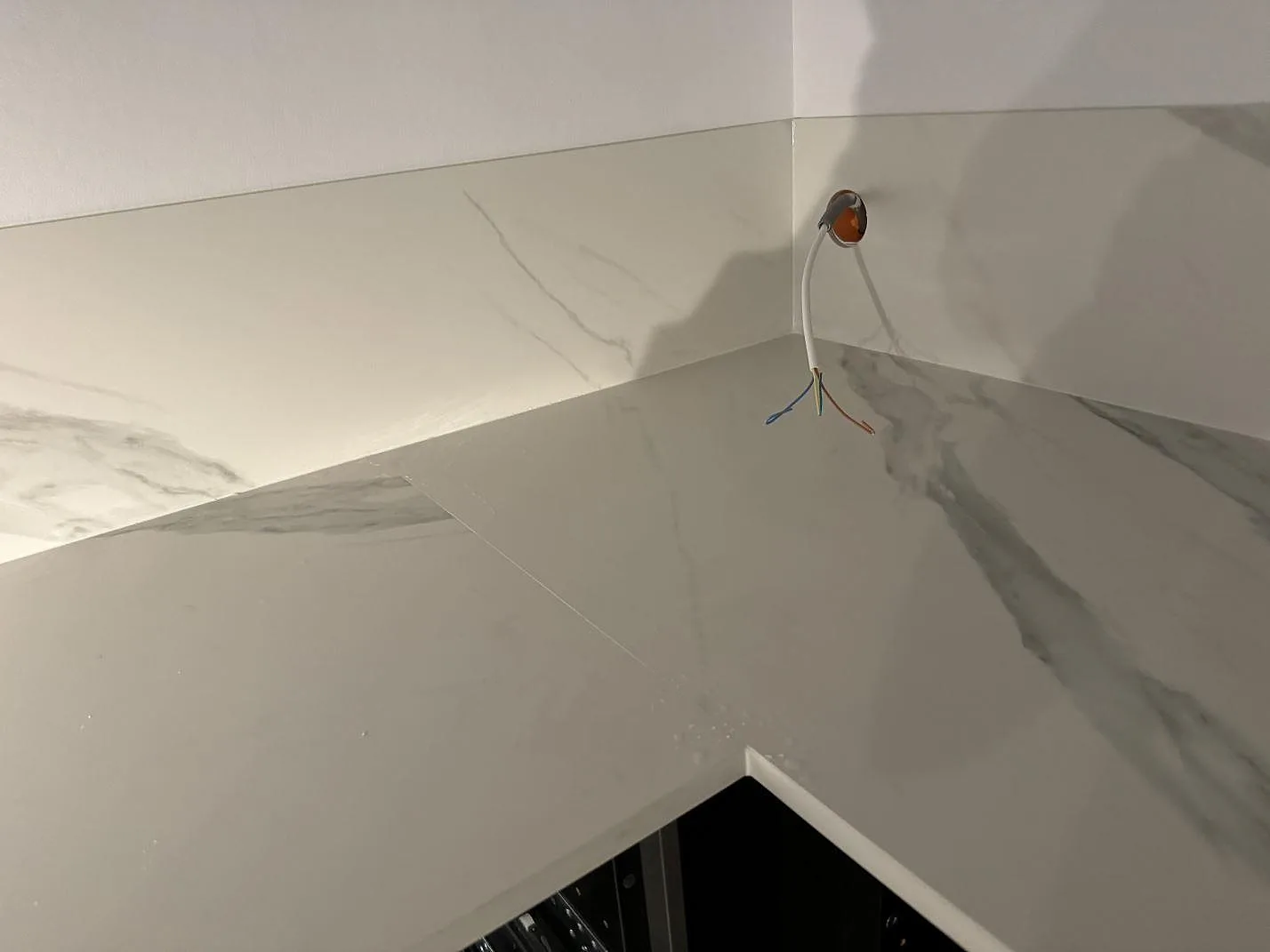 Installerad hörnyta i matt Dekton Opera Velvet med matchande stänkskydd och vägguttag under montering i Malmö.