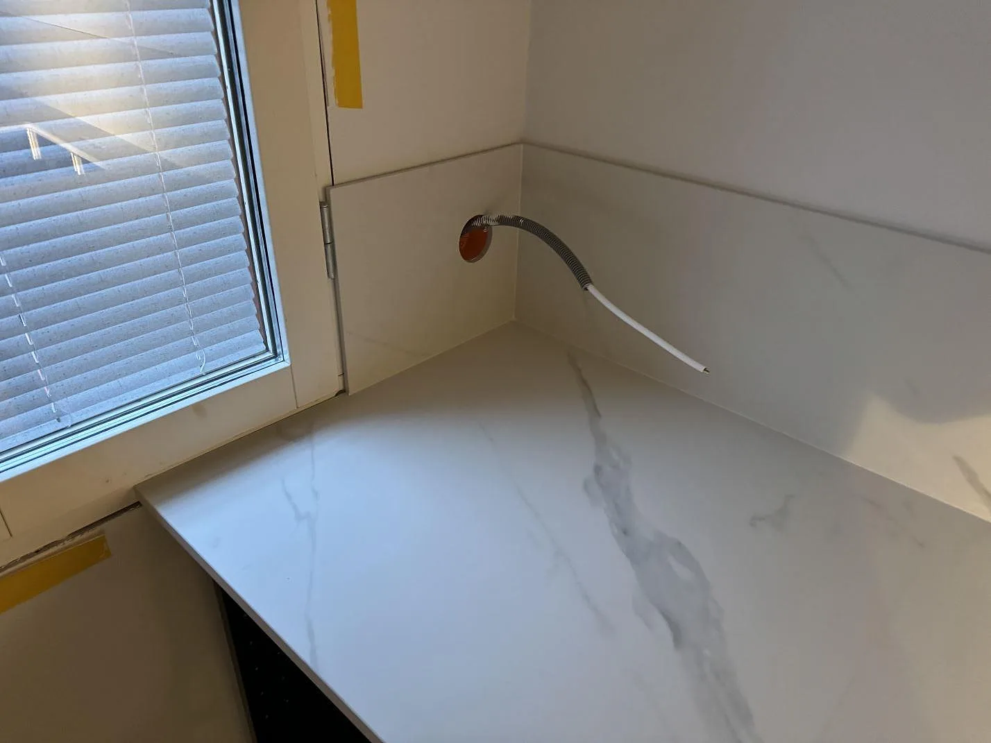 Hörndel av köksbänkskiva i matt Dekton Opera Velvet med uppvikt stänkskydd vid fönster i Malmö.