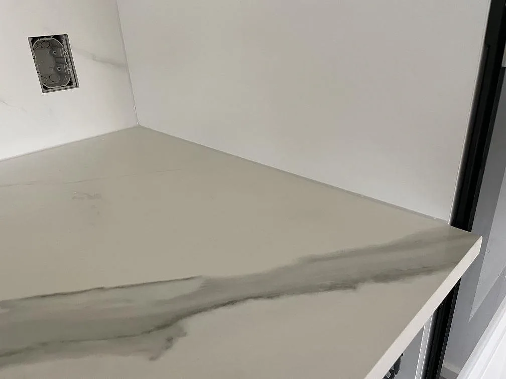 Hörn på installerad köksbänkskiva i matt Dekton Opera Velvet keramik med mjuk grå ådring vid svart fönster i Solroed Strand.