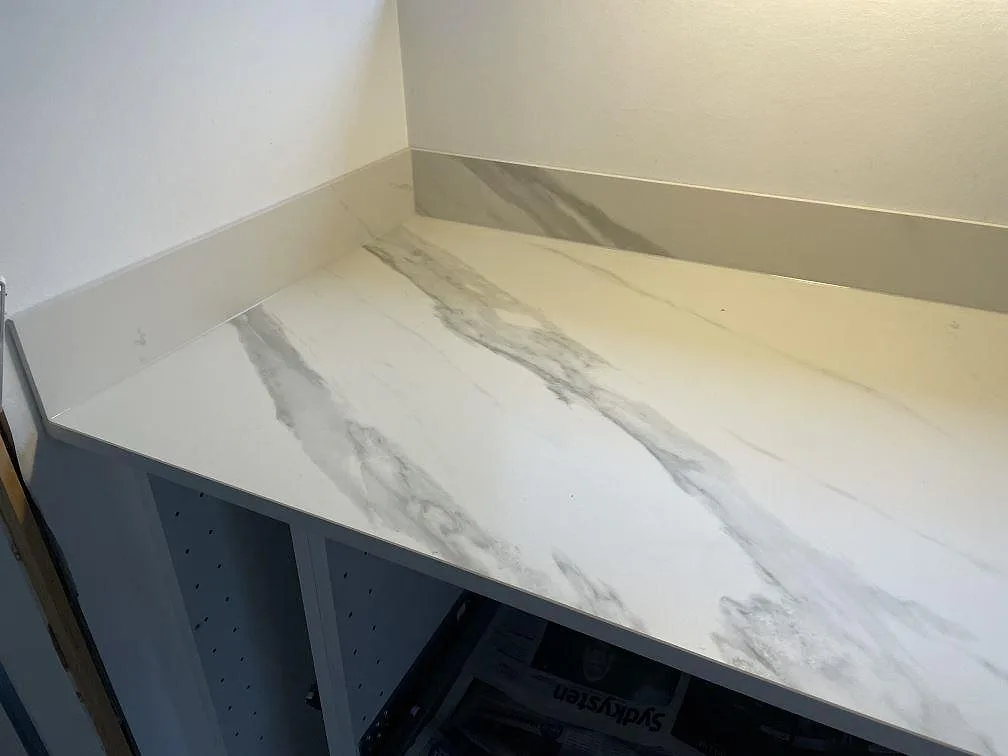 Detalj av matt Dekton Opera Velvet köksbänkskiva i keramik med uppvikt stänkkant och öppen köksstomme i Solroed Strand.