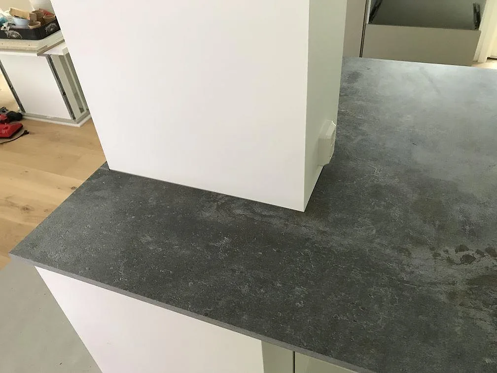Bänkskiva i Dekton Orix mot vit vägg, matt mörkgrå keramik med synlig stenkant, i ett kök i Sävedalen.