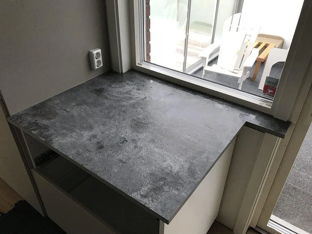 Köksbänkskiva i Dekton Orix vid fönstret, matt keramik i mörk betongton, monterad i ett kök i Sävedalen.
