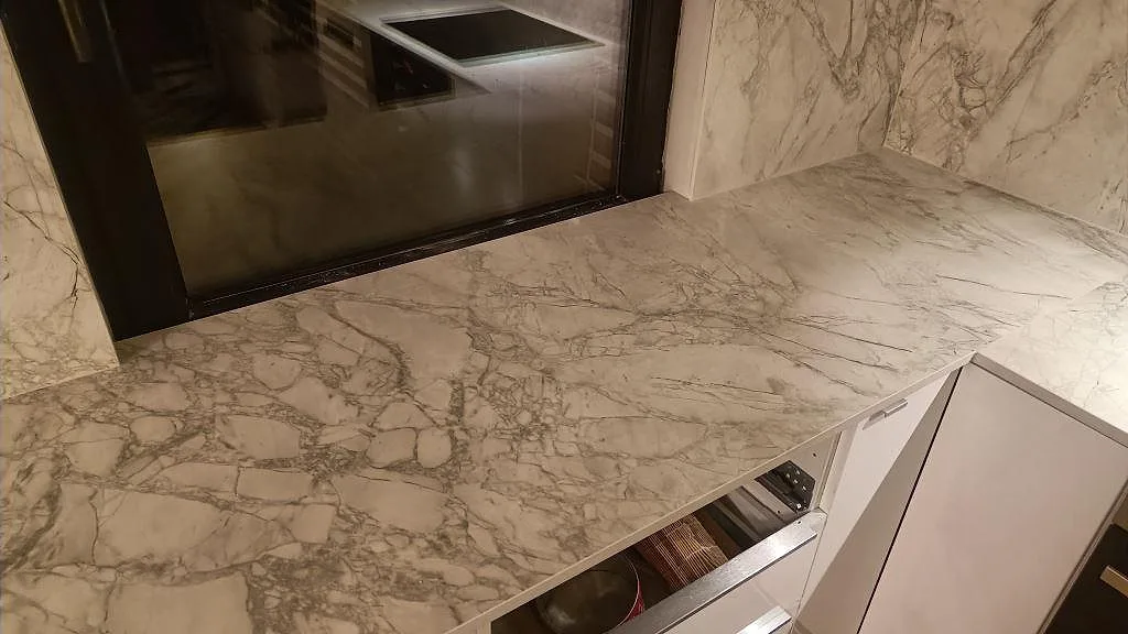 Närbild på matt Dekton Portum med ljus bas och grå ådring på köksbänk vid fönster i Malmö.
