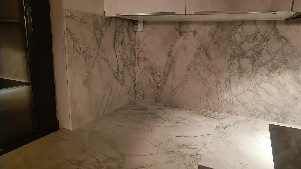 Hörn med bänkskiva och stänkvägg i matt Dekton Portum under överskåp i Malmö.