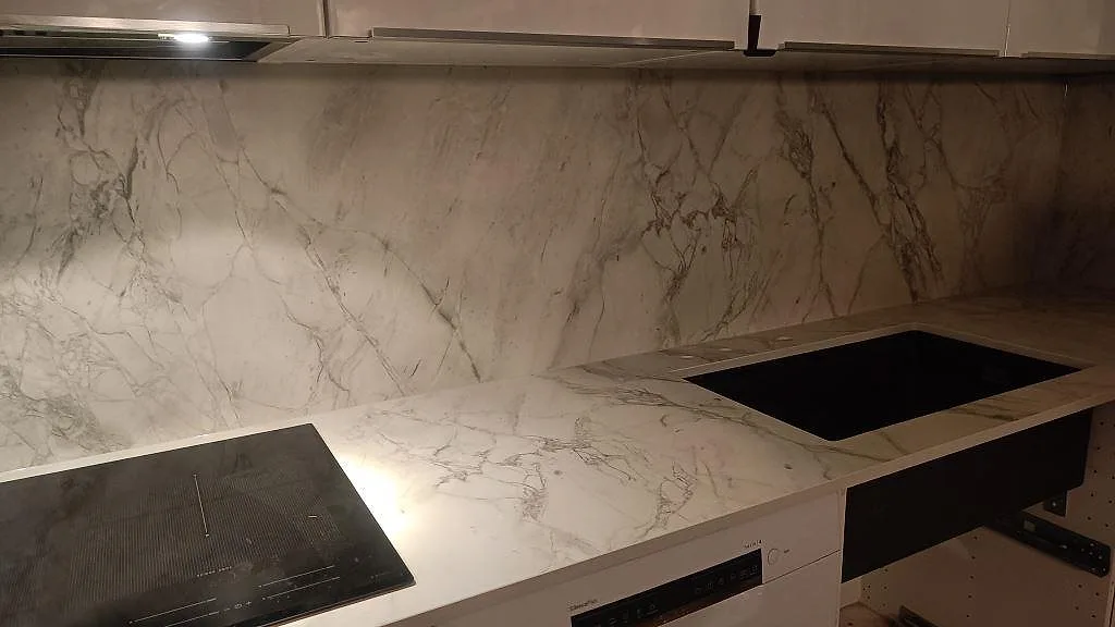 Matt köksbänkskiva i Dekton Portum med svart häll, svart diskho och fullhöjd stänkvägg i ett kök i Malmö.