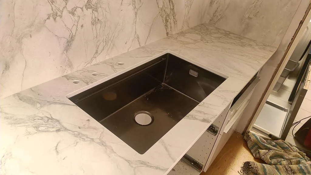 Svart underlimmad diskho i matt Dekton Portum med ljusgrå ådring i ett Malmö-kök.