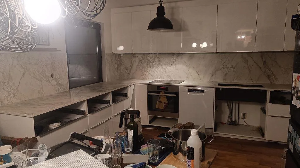 Köksbänkskiva och stänkvägg i matt Dekton Portum under montering i ett vitt kök i Malmö.