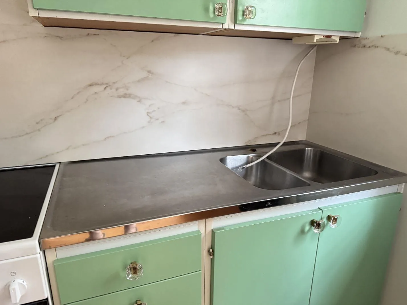 Stänkskydd i matt Dekton Rem (Velvet) bakom rostfri bänkdel och fristående spis i ett kök i Åhus.