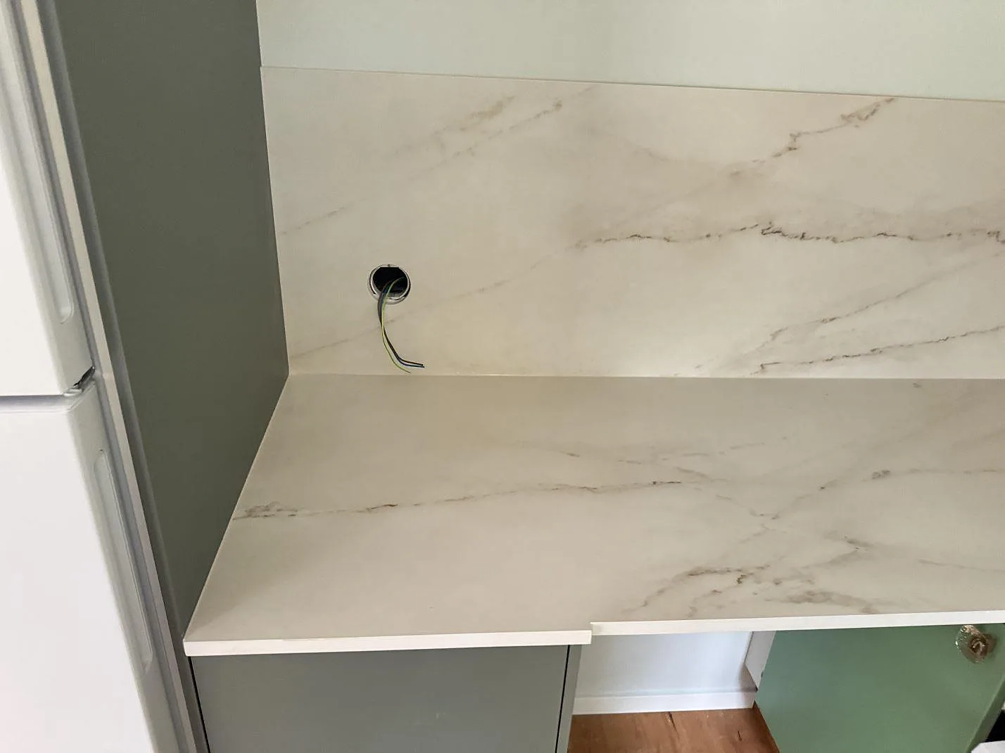 Närbild på ljus köksbänkskiva i matt Dekton Rem (Velvet) med 8 mm stänkskydd och grå ådring i Åhus.