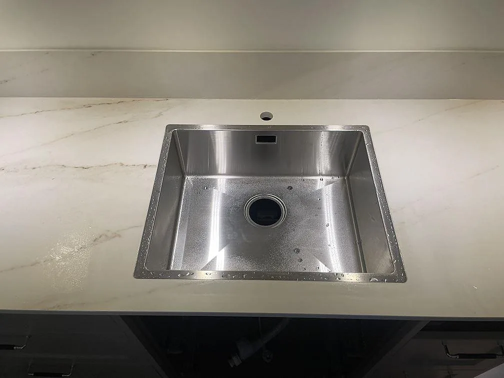 Närbild på Dekton Rem (Velvet), matt keramik, med rostfri diskho och ljus ådring i köket i Åskloster.
