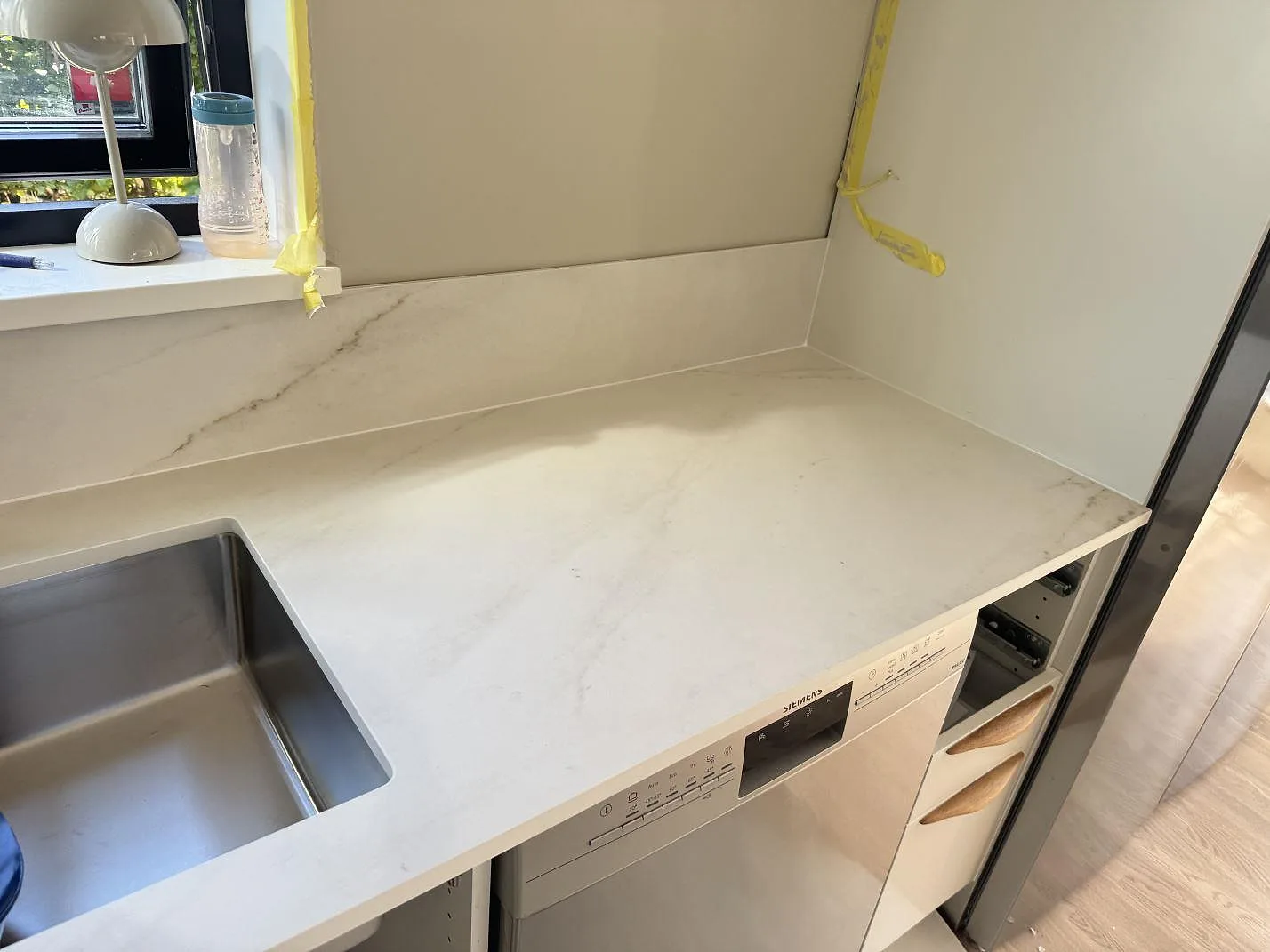 Arbetsyta i matt Dekton Rem (Velvet), keramik, med underlimmad diskho, diskmaskin och låg stänkkant i ett kök i Båstad.