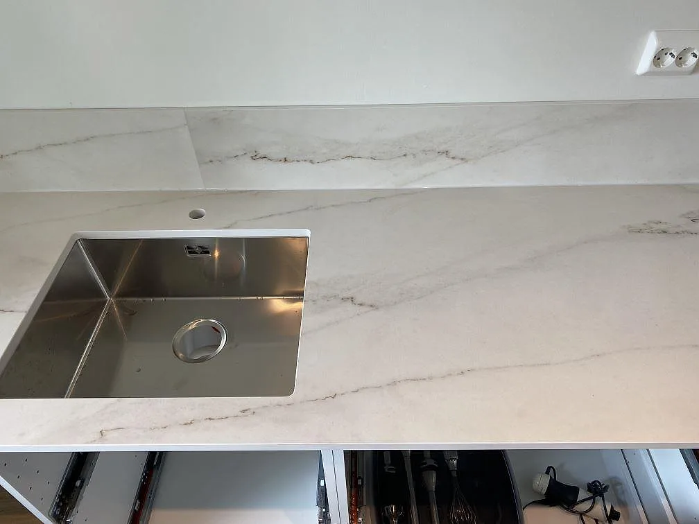 Underlimmad rostfri diskho i matt Dekton Rem Velvet köksbänkskiva med tunt stänkskydd och kran i ett kök i Ellös.