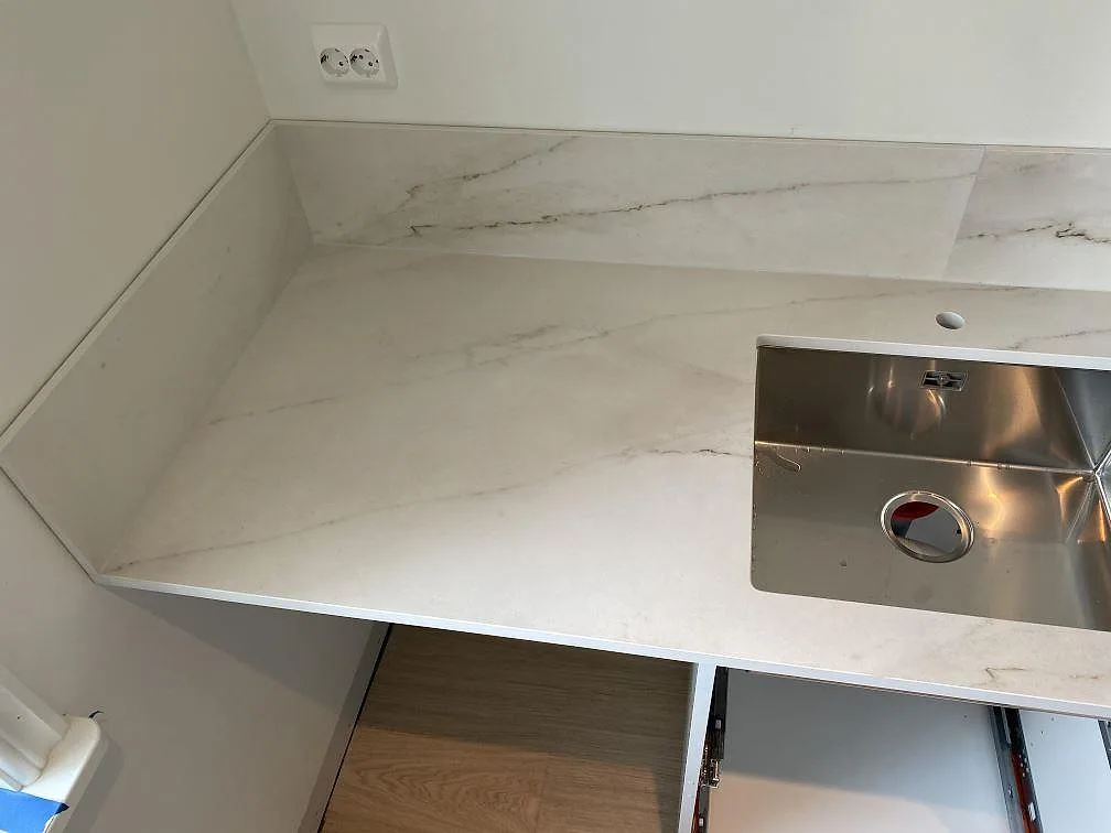Matt Dekton Rem Velvet bänkskiva med underlimmad rostfri diskho och uppvikt stänkkant i hörnet av ett kök i Ellös.