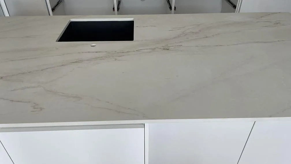 Detalj av köksbänkskiva i matt Dekton Rem (Velvet), vit keramik med grå ådring och diskhozon i Hvidovre.