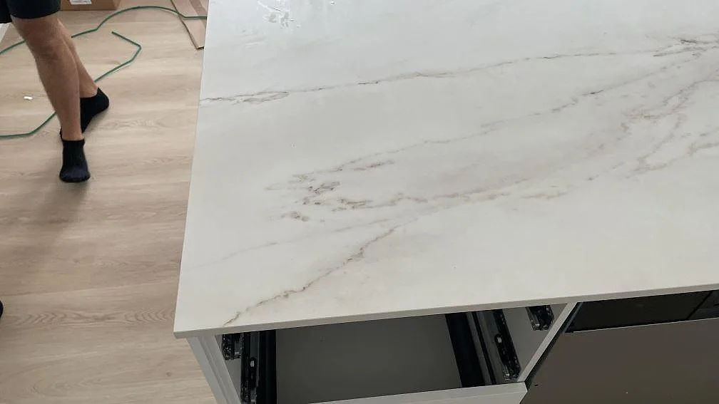 Monteringsbild av matt Dekton Rem (Velvet) på köksö, ljus keramisk bänkskiva med öppen lådstomme i Hvidovre.