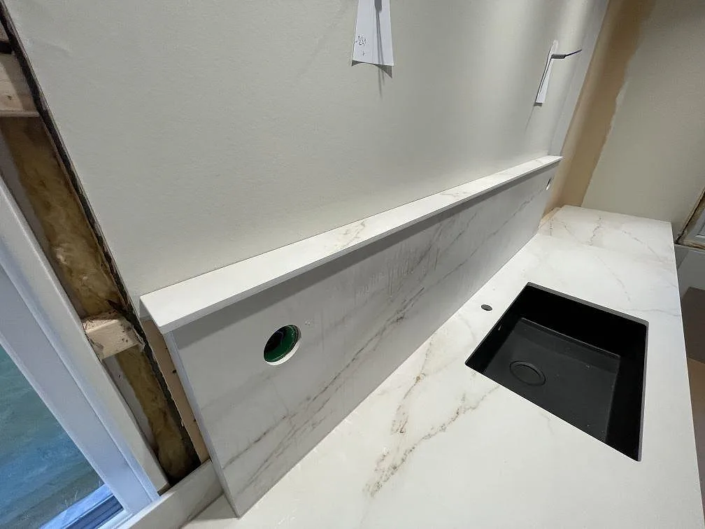 Närbild på svart diskho och separat blandarhål i köksbänkskiva av matt Dekton Rem (Velvet) med matchande stänkskydd i Kristinehamn.