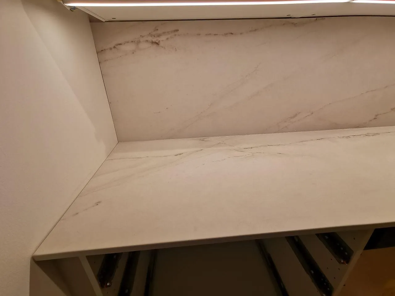 Närbild på den ljusa grå ådringen i en matt Dekton Rem Velvet keramikbänkskiva med uppvikt stänkskydd i ett kök i Limhamn.